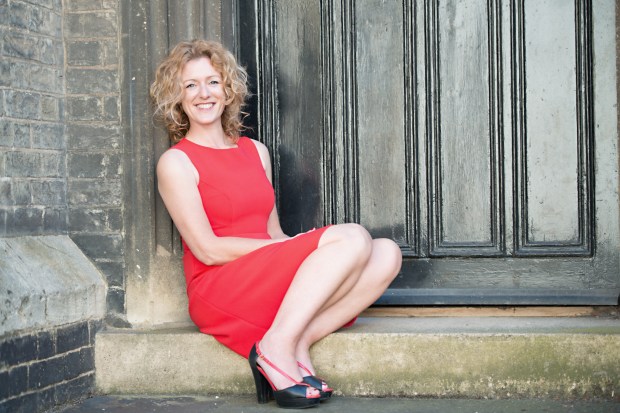 Woman in red dress sitting on steps in front of a door.