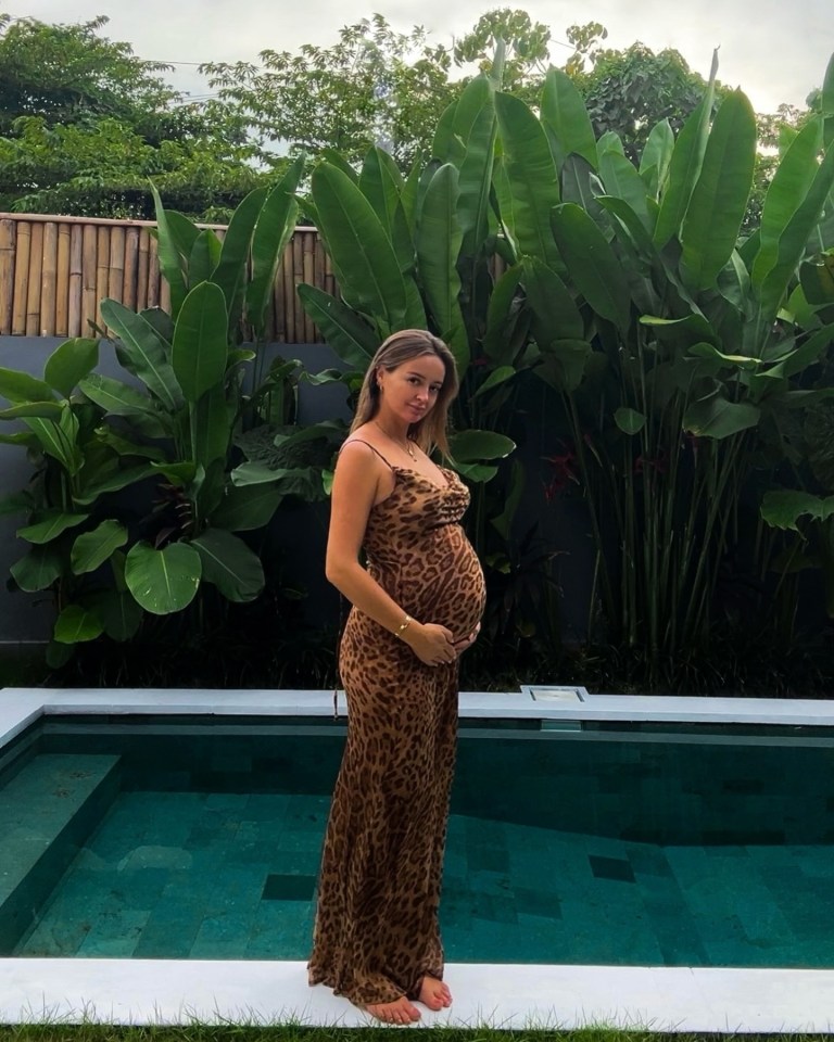 Pregnant woman in leopard print dress by a pool.