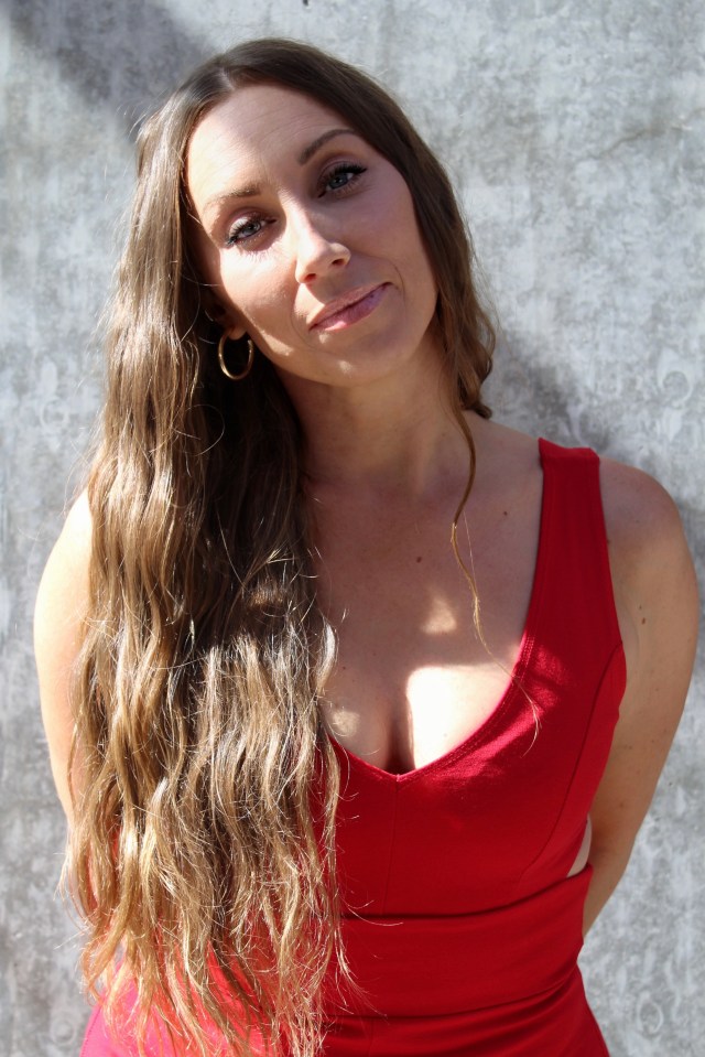 Woman with long brown hair wearing a red dress.