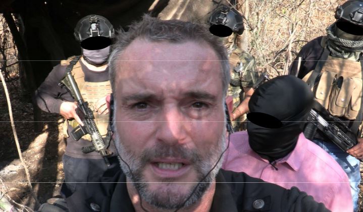 A man taking a selfie with armed men in Mexico.