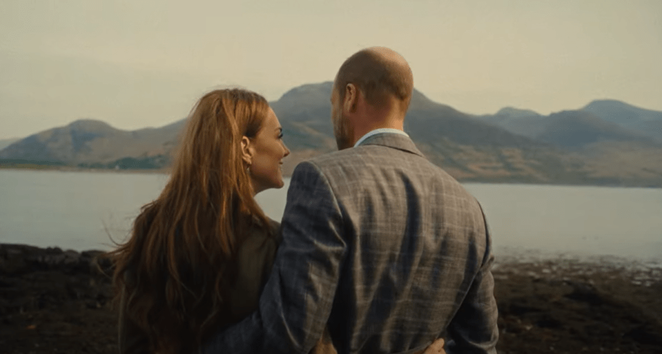 Couple embracing, overlooking a lake and mountains.