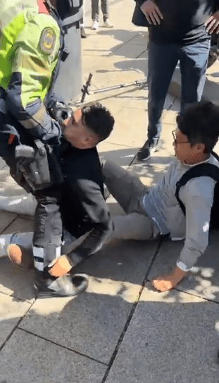 Police officer arresting a man on the ground.
