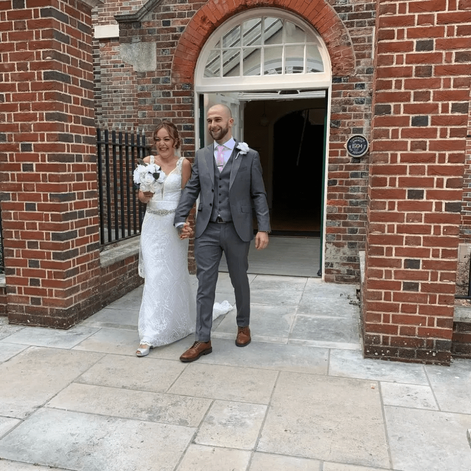 Newlywed couple leaving a brick building.