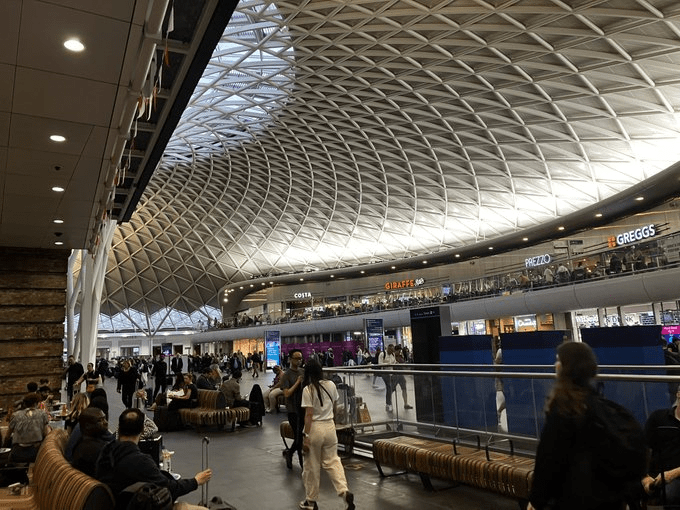 Interior of a train station with a large, arched ceiling and shops on a second level.