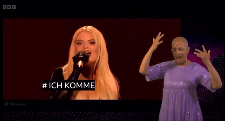 Singer performing on stage with a sign language interpreter.