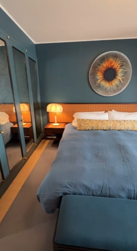 Graham Norton's New York bedroom with teal walls, a large iris print, and a blue bed.