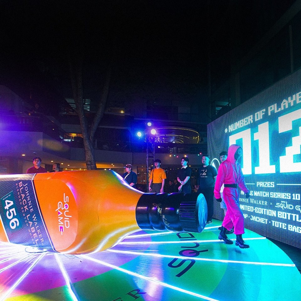 Giant Johnnie Walker bottle at a Squid Game-themed event.