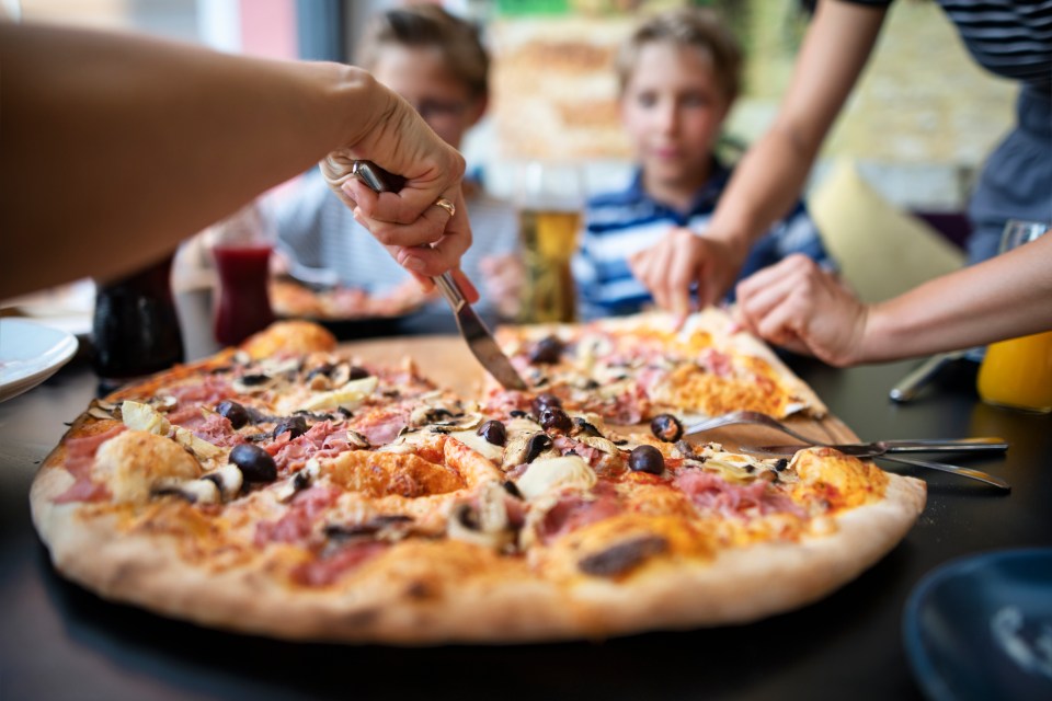 Kids sharing a large pizza at a restaurant.