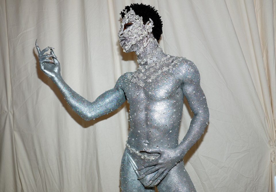Person in silver glitter body paint and jeweled adornments at the Met Gala.