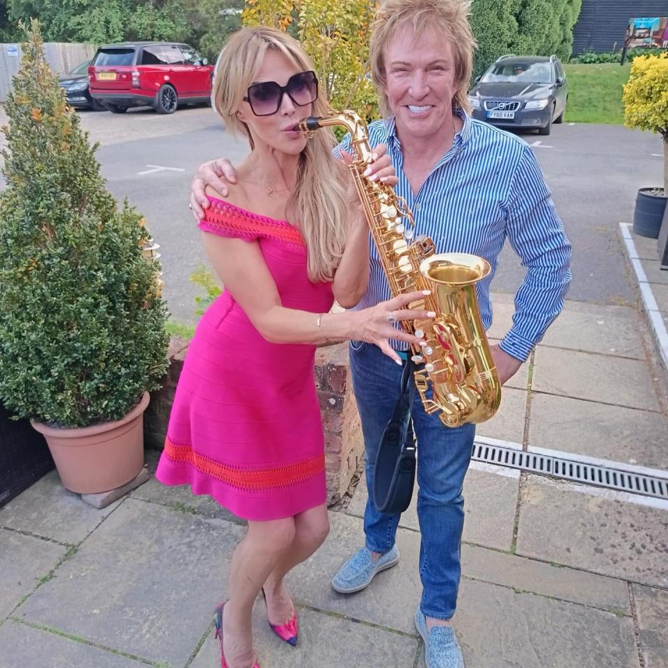Woman in pink dress and man in blue shirt holding a saxophone.