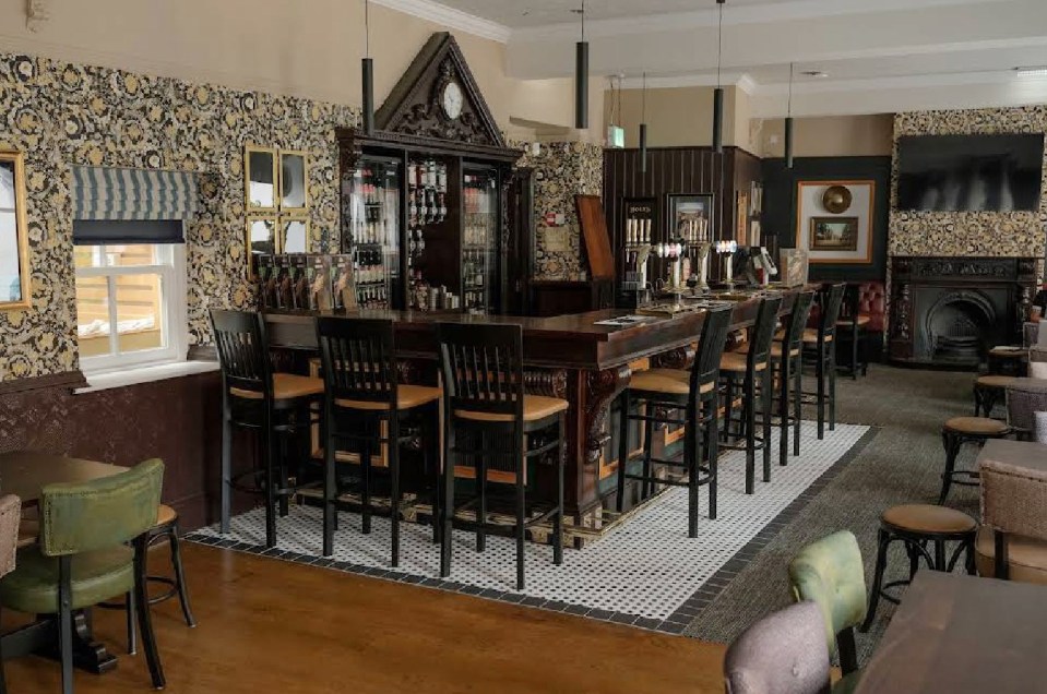 Interior view of a pub with a long bar and several bar stools.