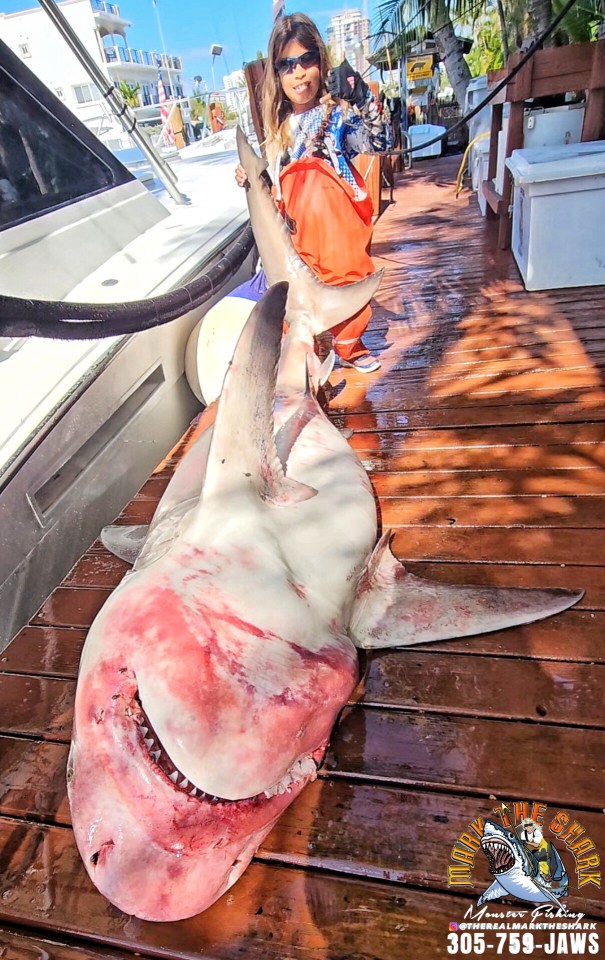 Girl holding a large shark on a dock.