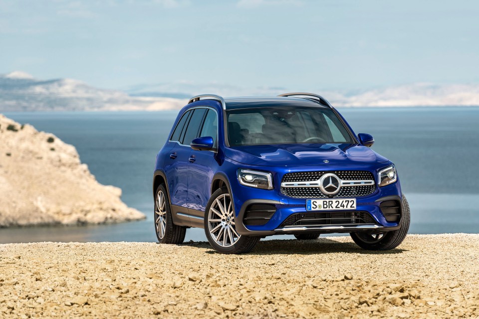 Blue Mercedes-Benz GLB parked on a rocky surface overlooking the ocean.