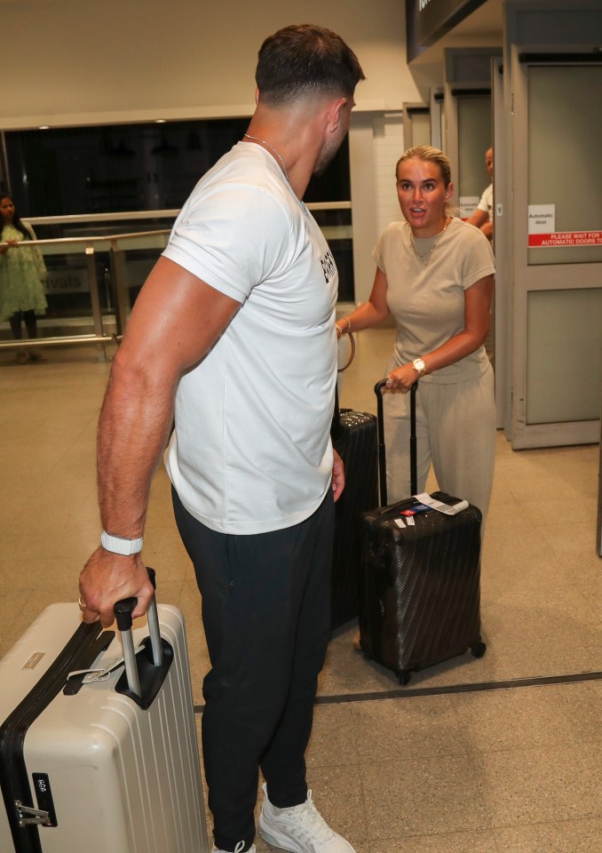 Molly Mae and Tommy Fury arriving at an airport with luggage.