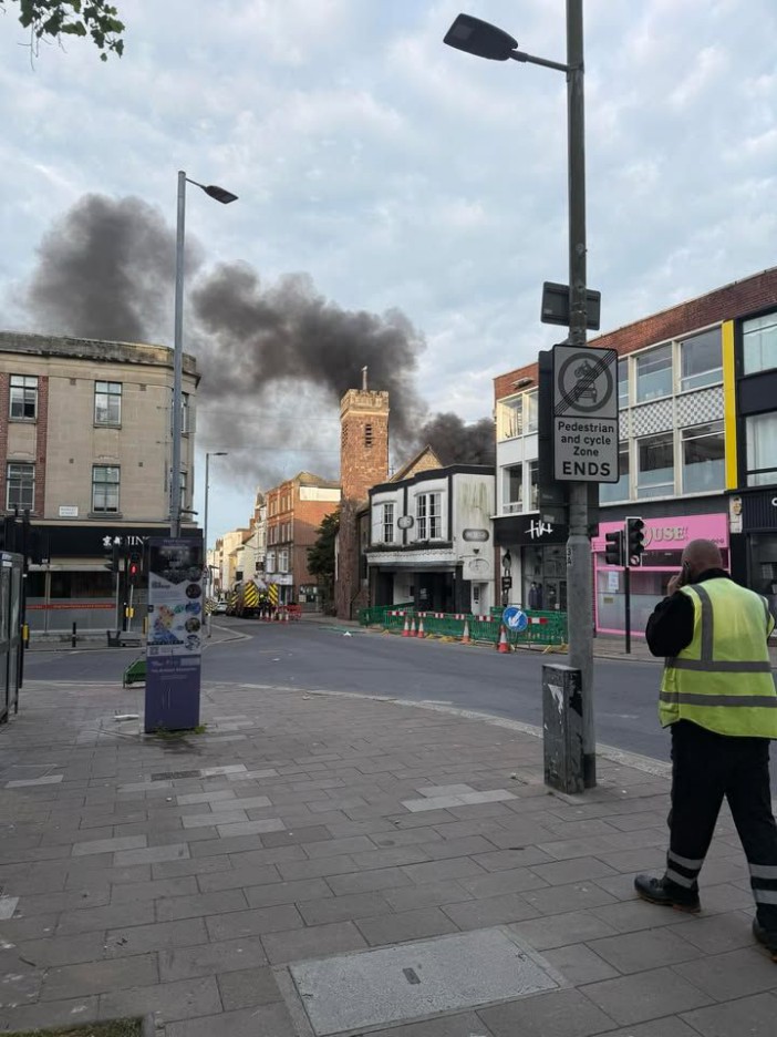 Black smoke billowing over buildings in a city street.