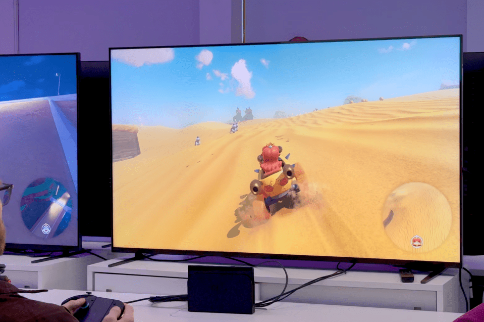 Person playing a video game featuring a vehicle driving through a desert.