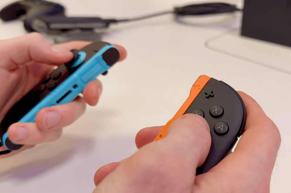 Two hands holding Nintendo Switch controllers.