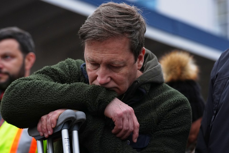 A grieving man leans on crutches at a vigil.