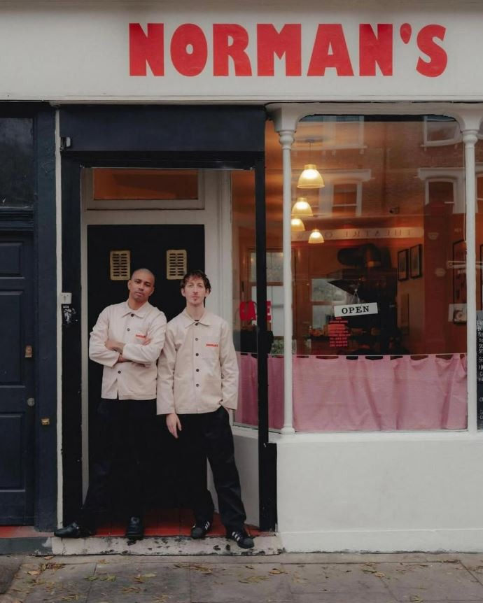 Two men standing in front of Norman's Cafe in London.
