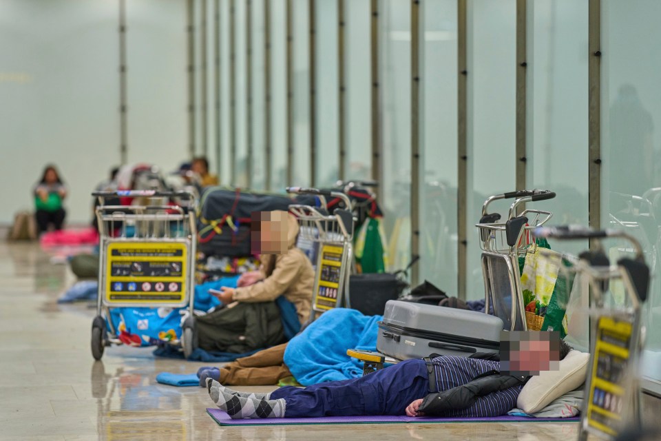 People sleeping on the floor of an airport terminal.