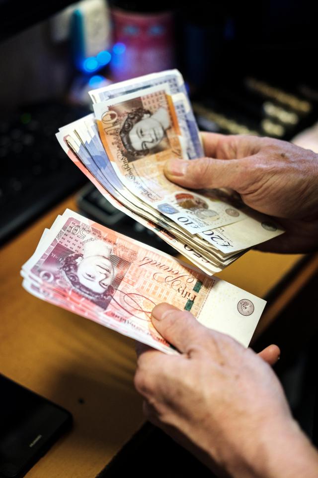 Hands counting British pound banknotes.