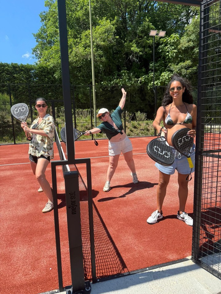 Three women playing paddle tennis. One woman is pregnant.