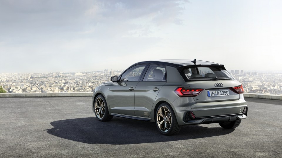 Rear view of a gray Audi A1 Sportback parked on a rooftop overlooking a city.