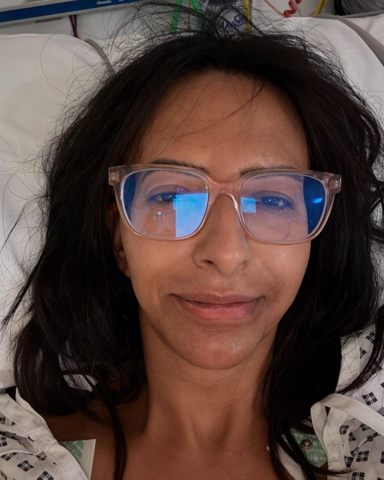 Woman in hospital gown wearing glasses.