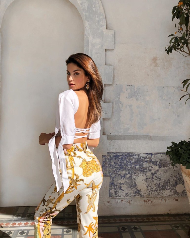 Woman in white top and patterned pants.