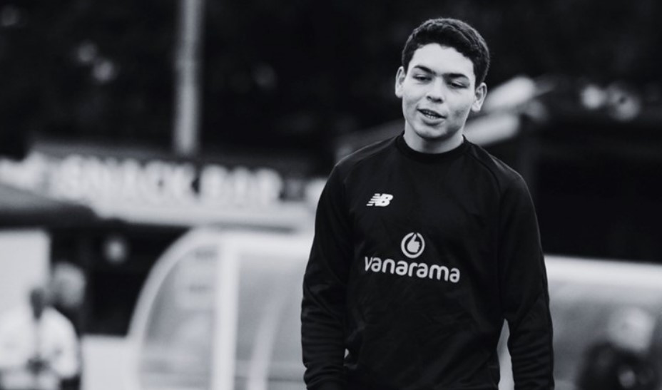 Black and white photo of a young man wearing a black sweatshirt with a logo.