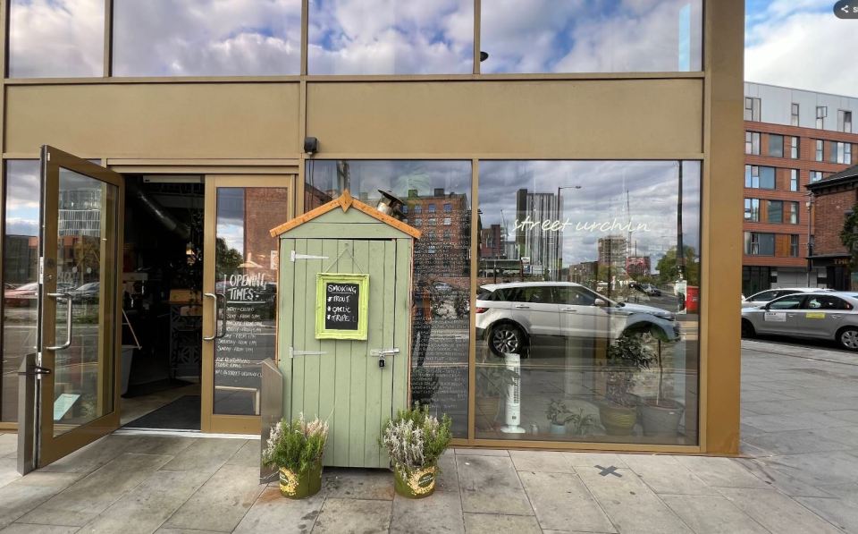 Exterior view of Street Urchin restaurant, showing the entrance, menu board, and opening times.