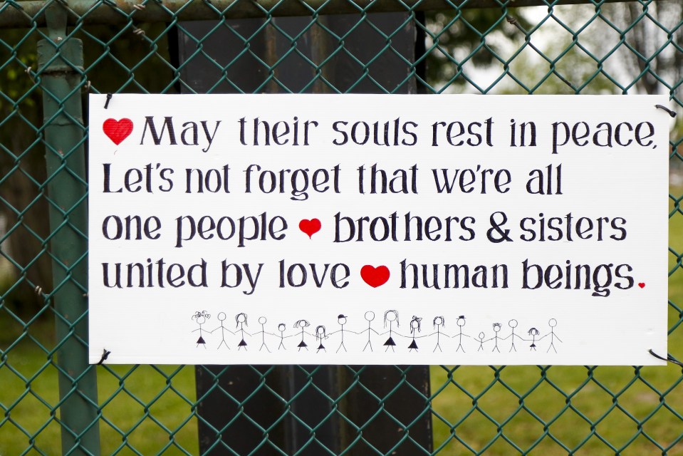 Sign reading "May their souls rest in peace. Let's not forget that we're all one people, brothers & sisters united by love, human beings." with a drawing of figures holding hands below.