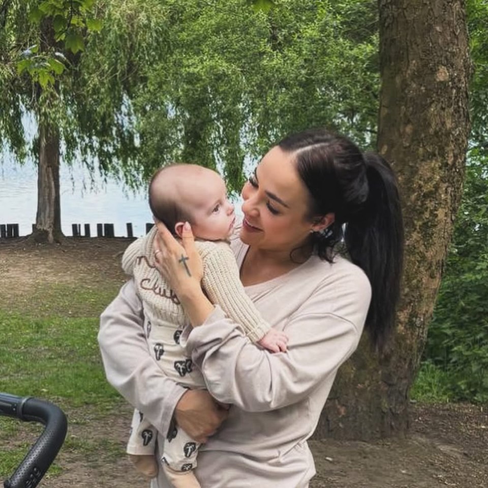 Woman holding and looking at her baby in a park.