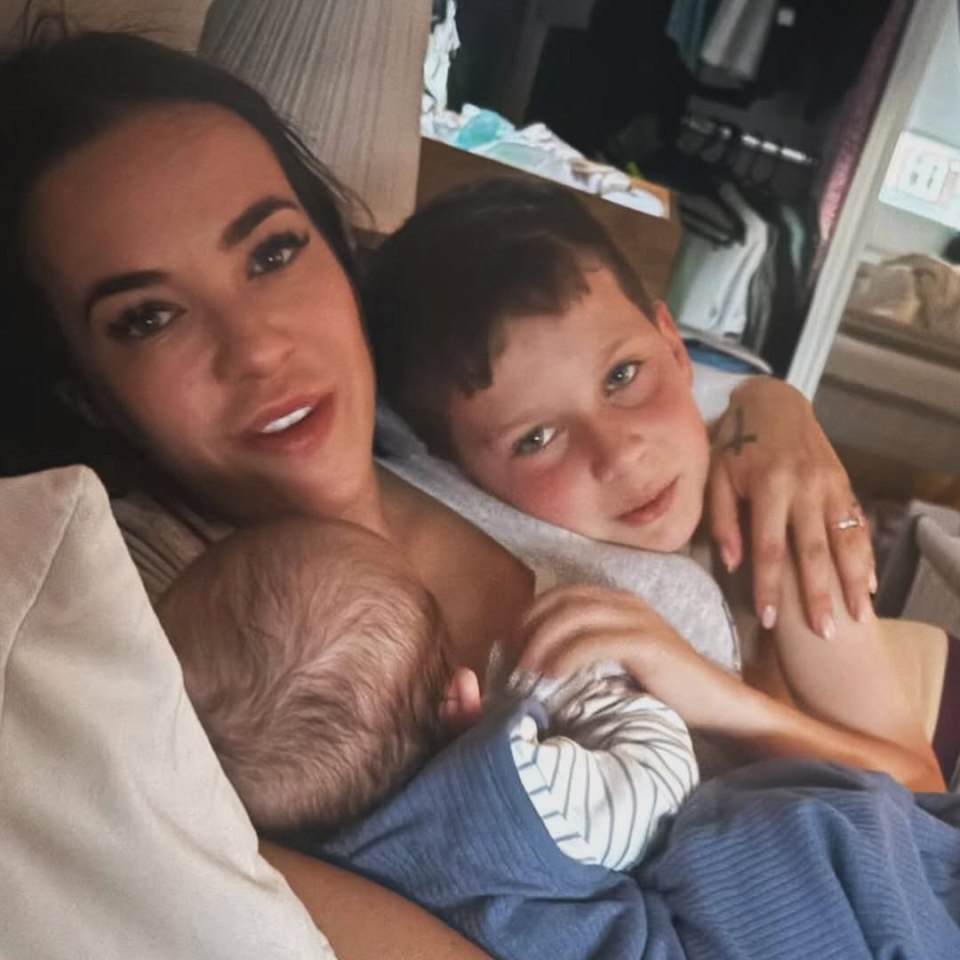 A woman cuddling her two young sons.