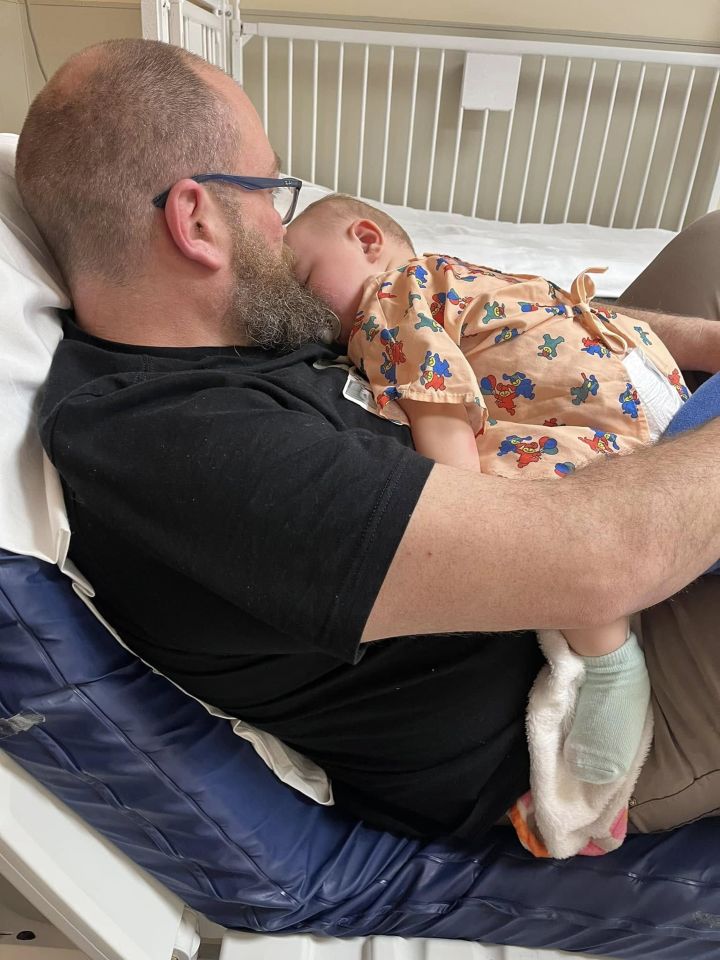 Father holding his baby daughter in a hospital bed.