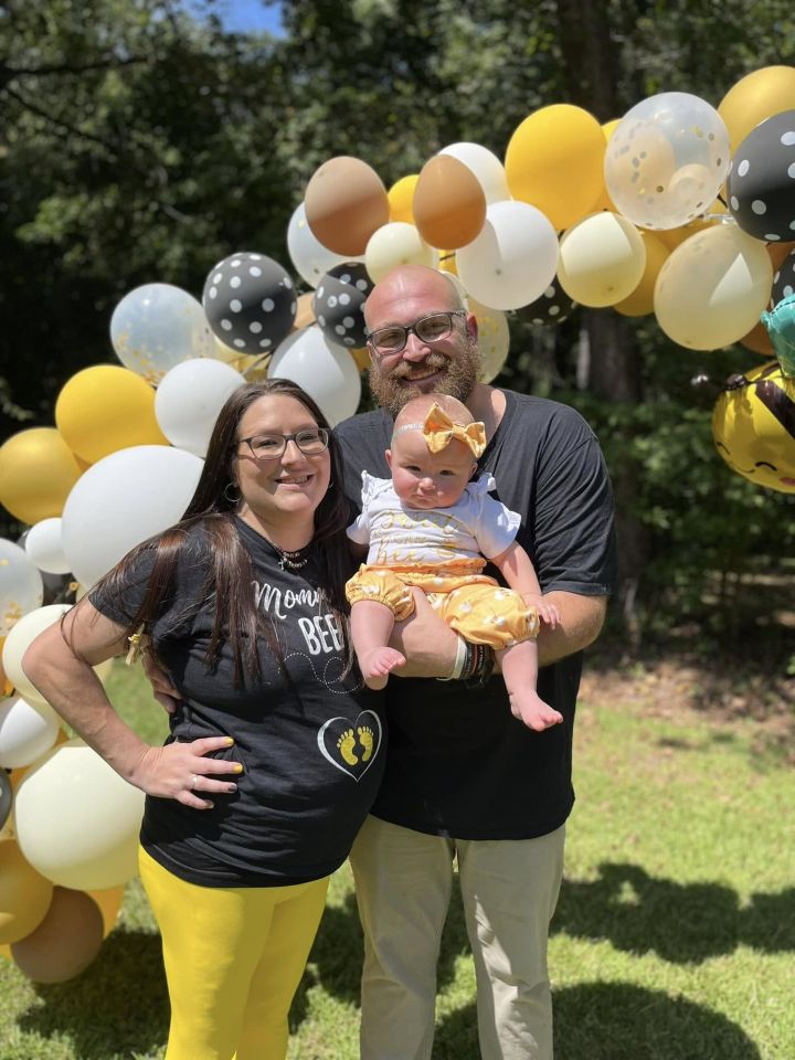 Family portrait with a baby in front of a balloon arch.