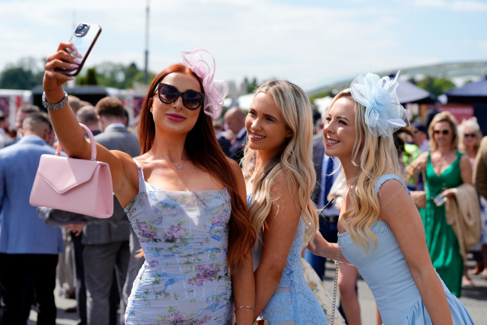 Three women at a racecourse taking a selfie.