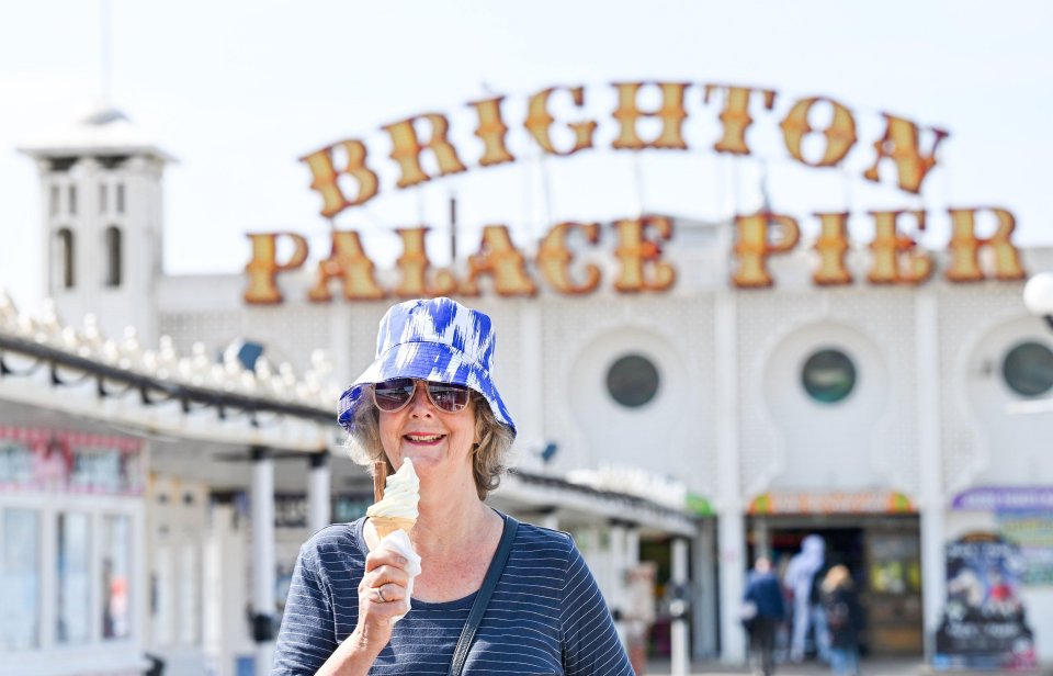 Woman eating ice cream in front of Brighton Palace Pier.