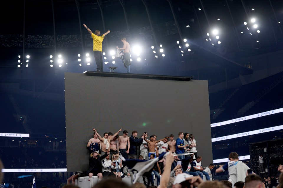 Tottenham Hotspur fans celebrating a win atop a large screen.