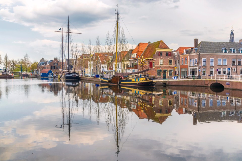 Weesp harbor with boats and historic buildings reflected in the water.