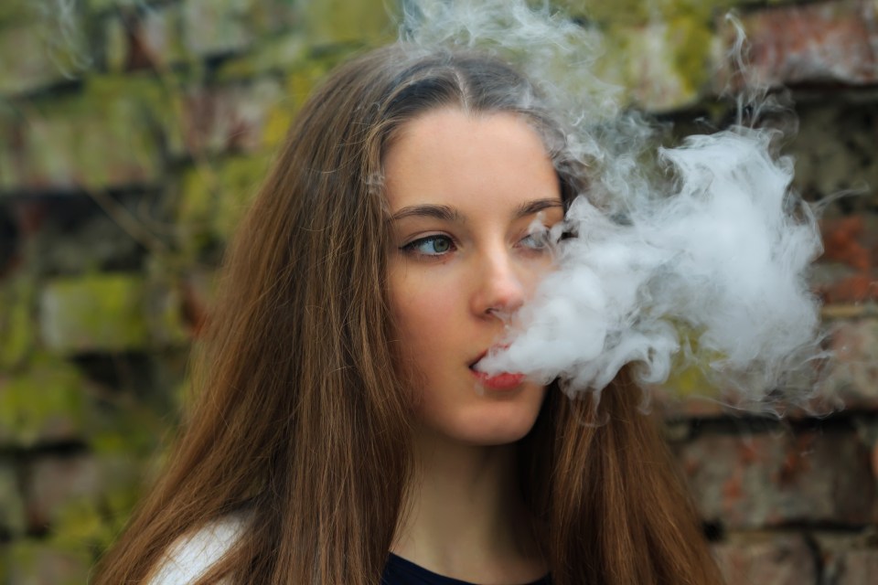 Teenage girl vaping outdoors.