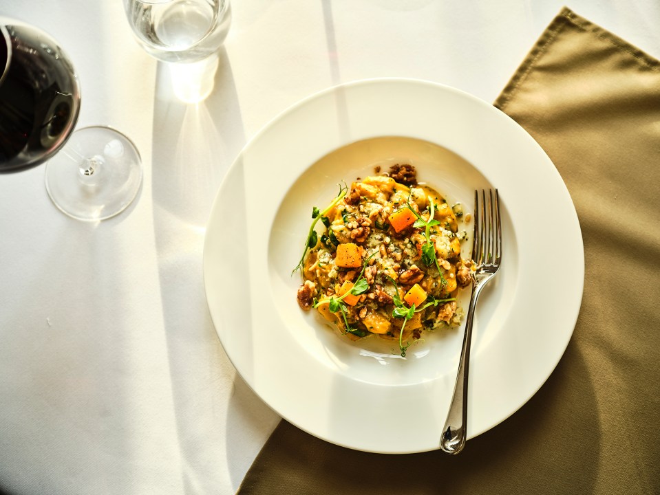 A plate of gnocchi with butternut squash, walnuts, and herbs.