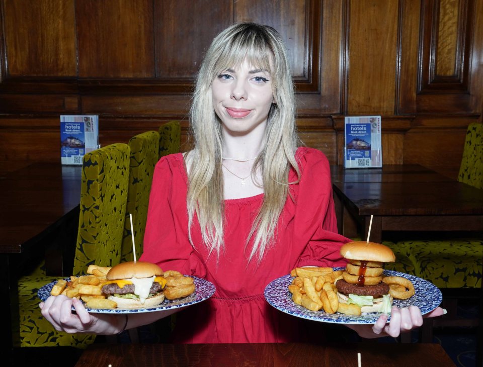 Woman holding two plates of Wetherspoon gourmet burgers and fries.