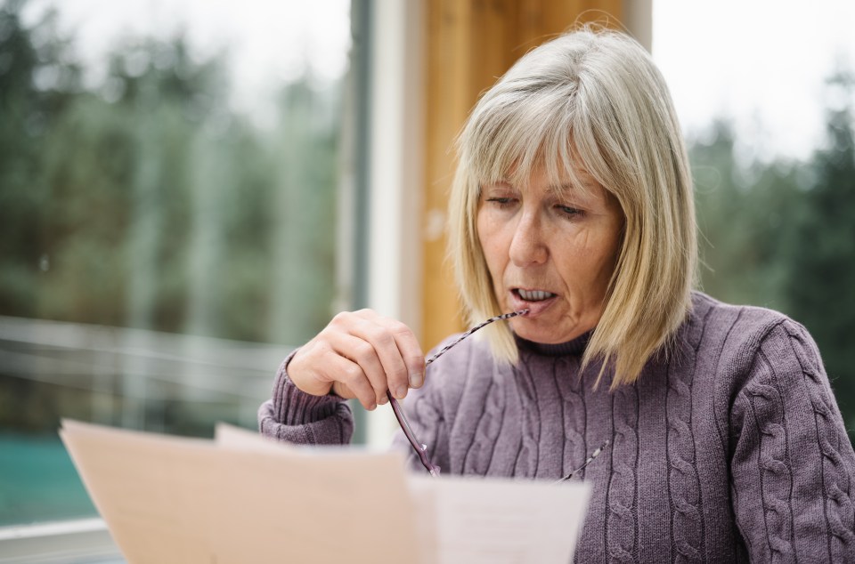Worried senior woman reviewing a bill.