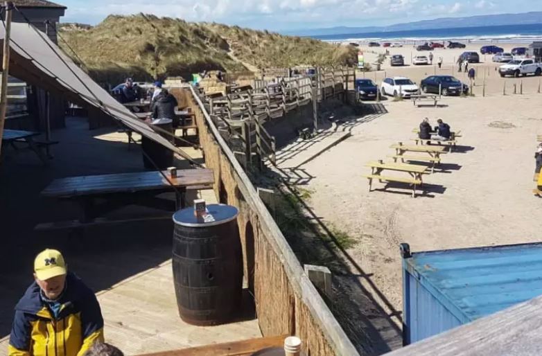 Outdoor beer garden with picnic tables near the beach.