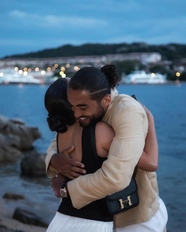 Couple embracing by the ocean at dusk.