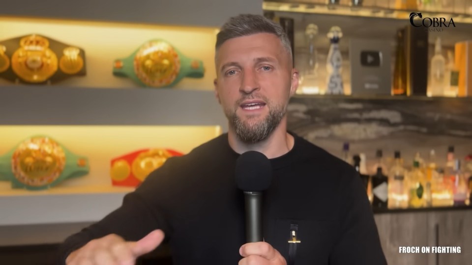 Carl Froch speaking into a microphone.  Boxing belts are visible in the background.