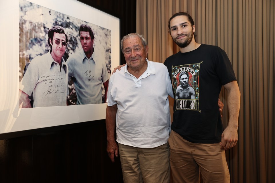 Two men posing with a signed photo of two boxers.