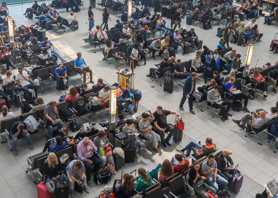 Person walking past airport departures board showing delayed flights.