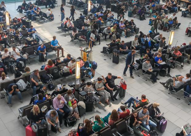 Person walking past airport departures board showing delayed flights.